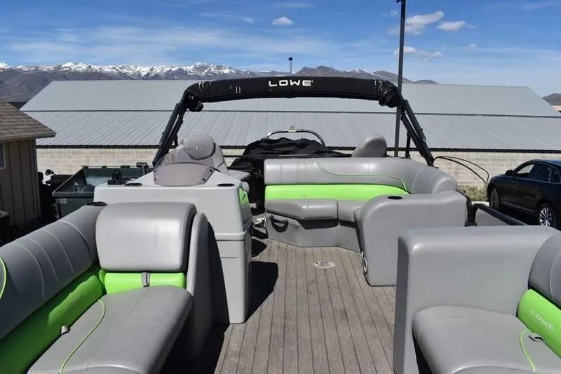 Slide: The Image of 2022 Lowe SF 212 Sport Fish pontoon boat with gray and green seating, mountain backdrop. - 15