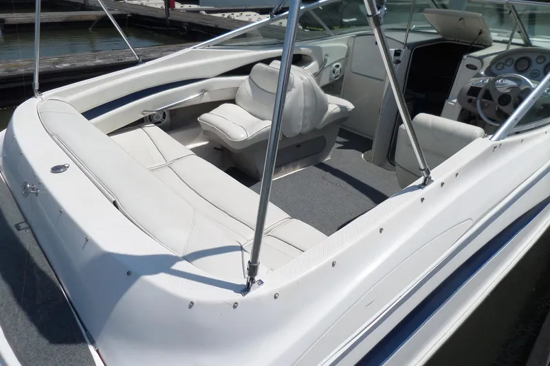Slide: The Image of 2003 Maxum 2400 SC boat interior with white seating and dashboard, docked at marina. - 6