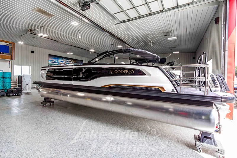 Slide: The Image of 2026 Godfrey Sanpan 2700 MTF pontoon boat in a showroom, sleek design and modern features. - 2