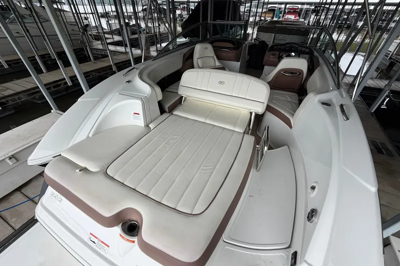 Slide: The Image of 2012 Cobalt 242 boat interior with white and brown seating, docked in a marina. - 18