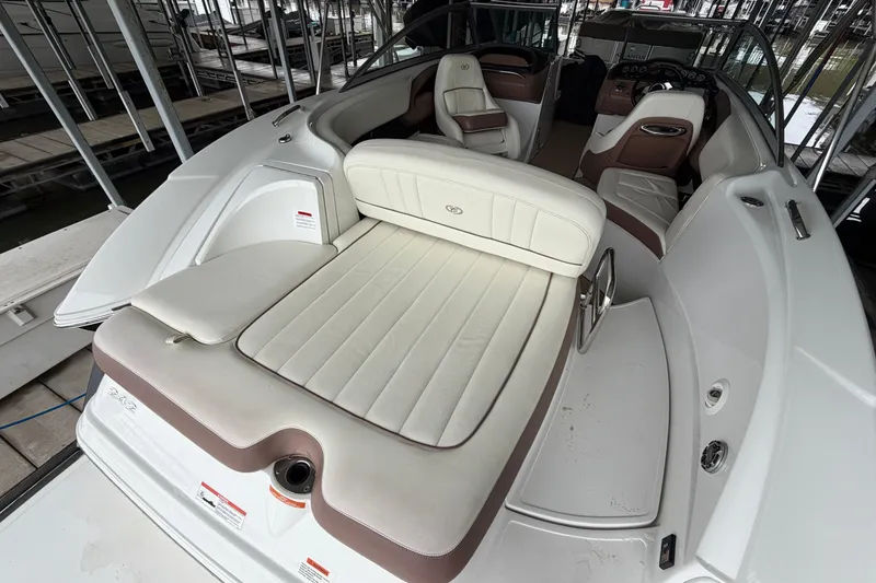 Slide: The Image of 2012 Cobalt 242 boat interior with white and brown seating, docked in a marina. - 19