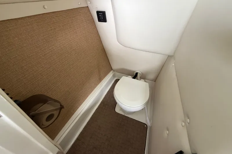 Slide: The Image of 2012 Cobalt 242 boat interior with compact marine toilet and beige carpeting. - 27