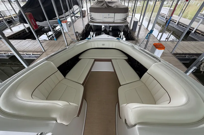 Slide: The Image of 2012 Cobalt 242 boat interior with beige seating, docked in a marina. - 29