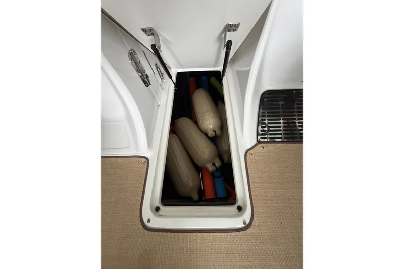 Slide: The Image of Storage compartment on a 2012 Cobalt 242 boat, containing boat fenders and accessories. - 33