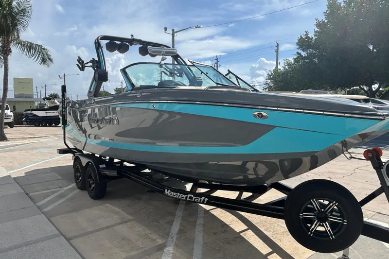 Slide: The Image of 2022 MasterCraft X26 boat on trailer, parked outdoors under a clear sky. - 13