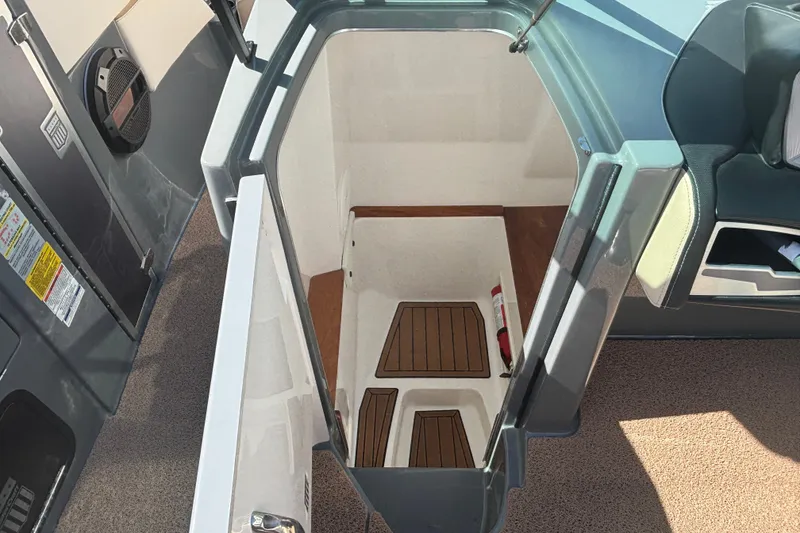 Slide: The Image of 2022 MasterCraft X26 boat interior storage compartment with wooden flooring and fire extinguisher. - 6