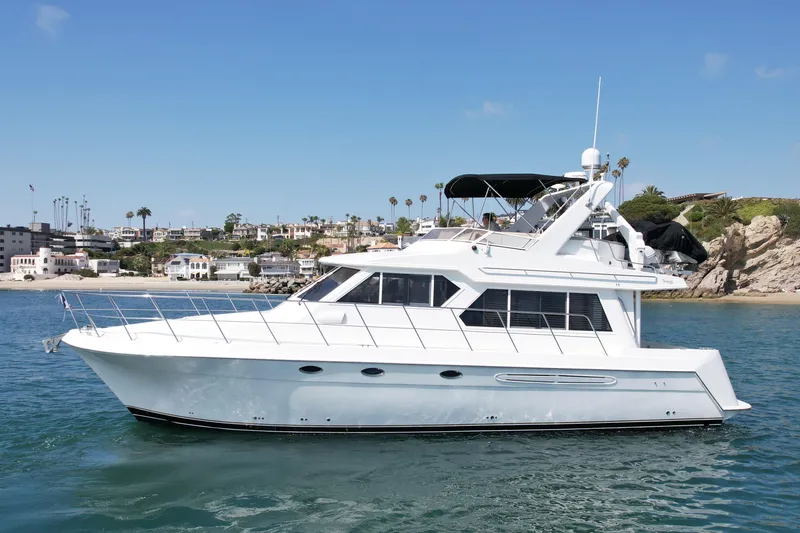 The Image of 2007 Navigator 44 Classic yacht cruising near coastal homes and rocky shoreline. - 0