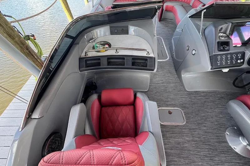 Slide: The Image of 2024 Bennington QX27 boat interior with red and gray seating, modern dashboard, and carpeted flooring. - 20