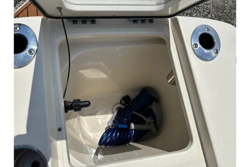 Slide: The Image of An open storage compartment on a boat with a blue hose inside. - 11
