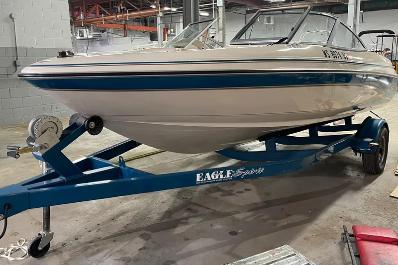 Slide: The Image of 1995 Glastron SSV 175 boat on a blue Eagle trailer in a warehouse setting. - 2