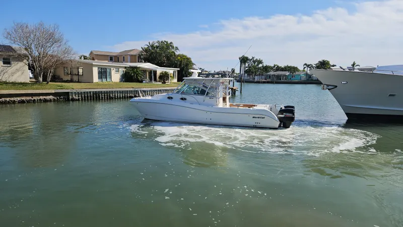 Slide: The Image of 2008 World Cat 320 EC boat cruising in a calm residential canal. - 17
