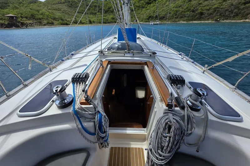 Slide: The Image of 2003 Bavaria 44 sailboat deck with ropes and open cabin, anchored in scenic bay. - 13