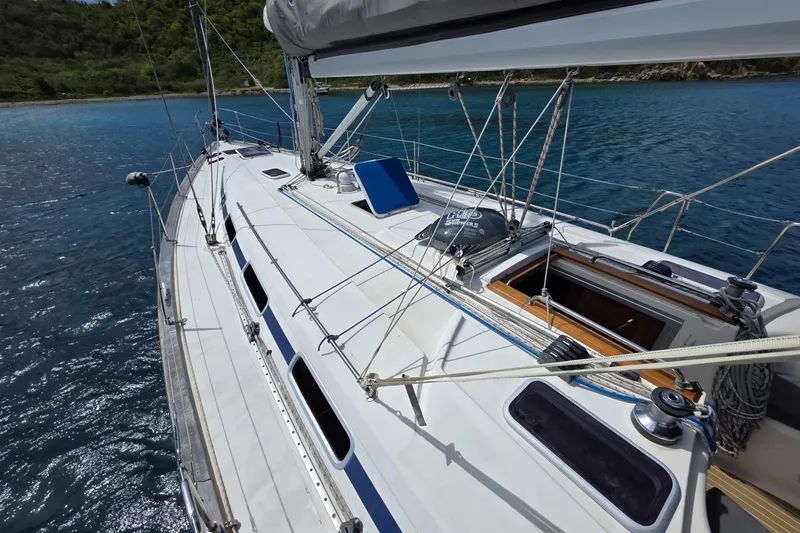 Slide: The Image of Sailing yacht Bavaria 44, 2003 model, cruising on clear blue waters near lush coastline. - 14