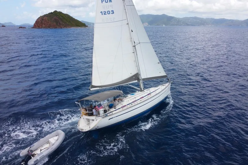 Slide: The Image of Sailing yacht Bavaria 44 (2003) cruising near an island in clear blue waters. - 2