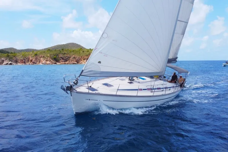 Slide: The Image of Sailing yacht Bavaria 44 (2003) cruising in clear blue waters near rocky coastline. - 3