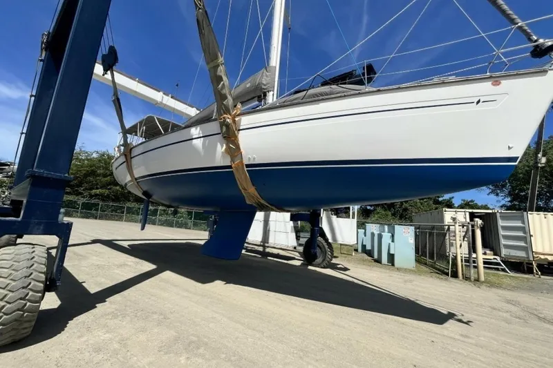 Slide: The Image of 2003 Bavaria 44 sailboat lifted by crane in a boatyard under clear blue sky. - 33
