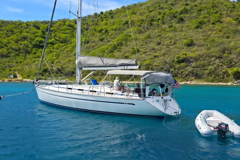 Slide: The Image of Sailing yacht Bavaria 44 (2003) anchored in clear blue waters near a lush green island. - 6