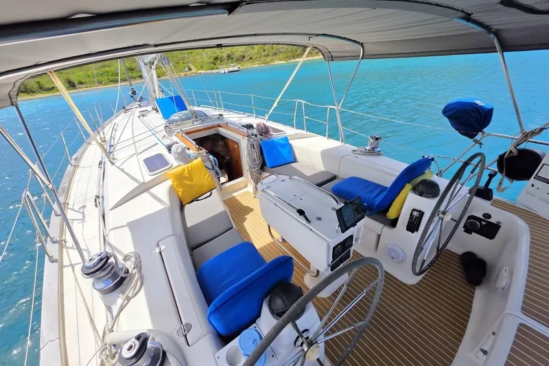 Slide: The Image of 2003 Bavaria 44 sailboat cockpit with blue cushions, steering wheels, and ocean view. - 7