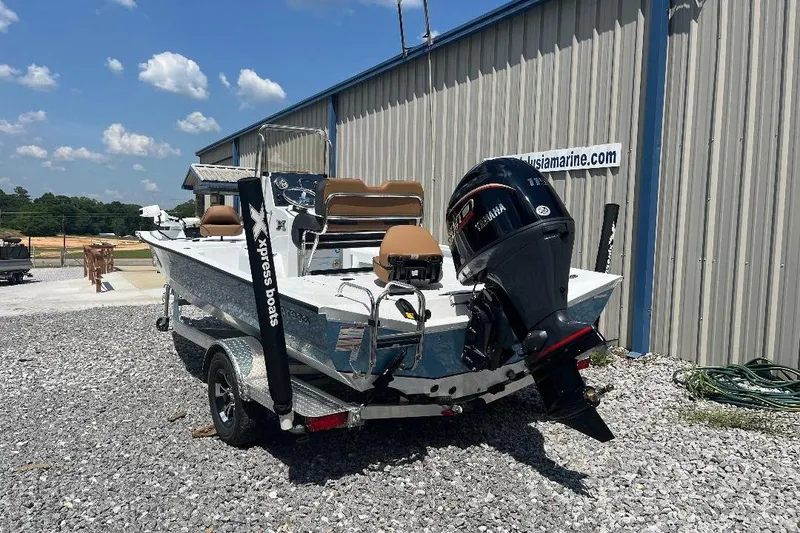 Slide: The Image of 2026 Xpress H20B Bay boat with Yamaha motor, parked on gravel near a metal building. - 12