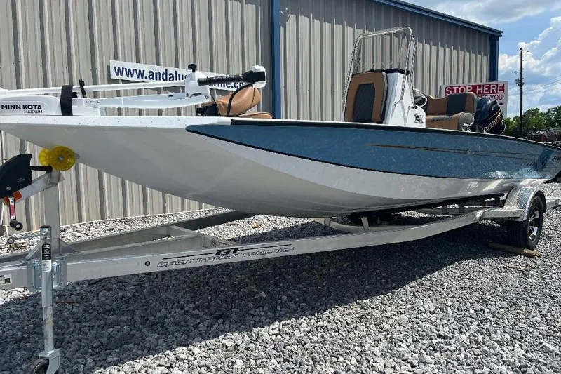 Slide: The Image of 2026 Xpress H20B Bay boat on trailer, featuring Minn Kota motor, parked on gravel. - 4