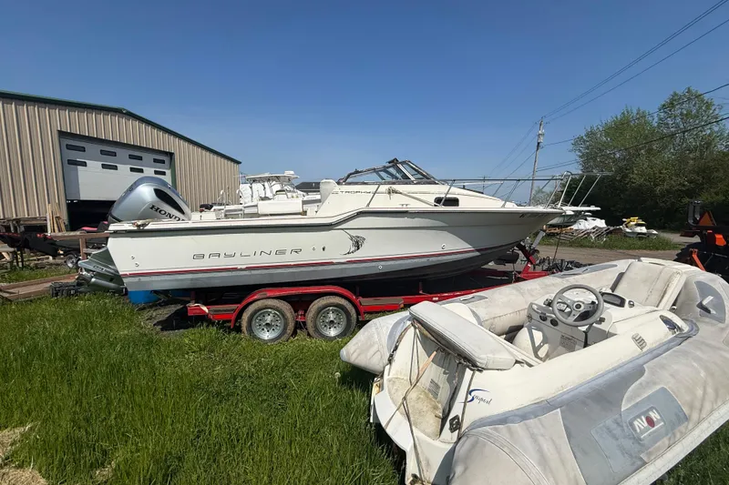 Slide: The Image of 1990 Bayliner 2302 Trophy Walkaround boat on trailer, parked near a warehouse. - 10