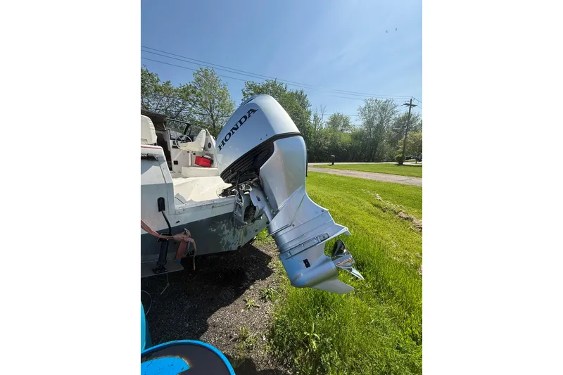 Slide: The Image of 1990 Bayliner 2302 Trophy Walkaround with Honda outboard motor in grassy area. - 8