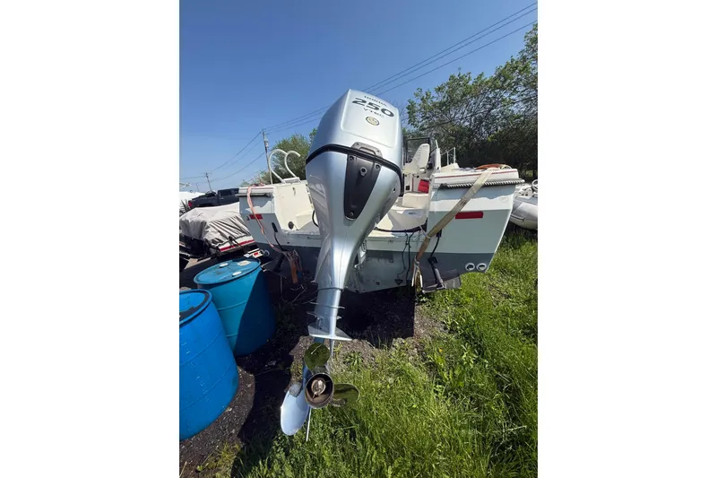 Slide: The Image of 1990 Bayliner 2302 Trophy Walkaround with outboard motor, parked on grass. - 9