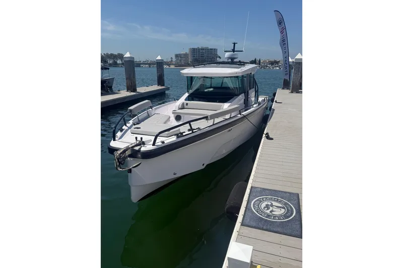 Slide: The Image of 2025 Axopar 29 XC Cross Cabin docked at marina under clear blue sky. - 1