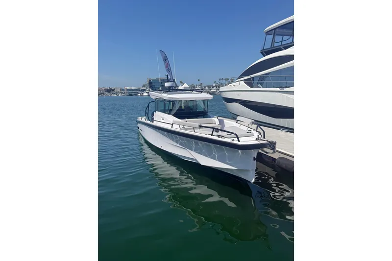 Slide: The Image of 2025 Axopar 29 XC Cross Cabin boat docked in a marina under clear blue skies. - 2