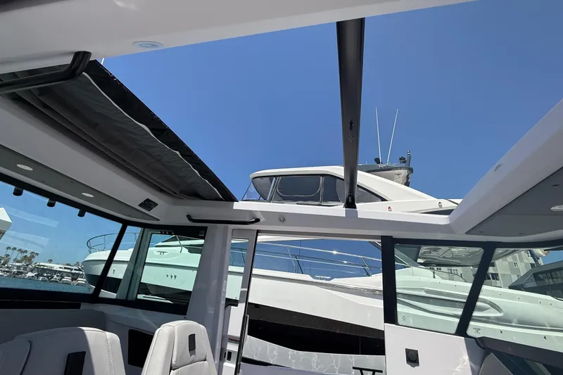 Slide: The Image of 2025 Axopar 29 XC Cross Cabin interior with open roof, docked near other boats. - 23