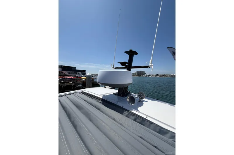 Slide: The Image of 2025 Axopar 29 XC Cross Cabin boat roof with radar and antennas, docked by the water. - 30