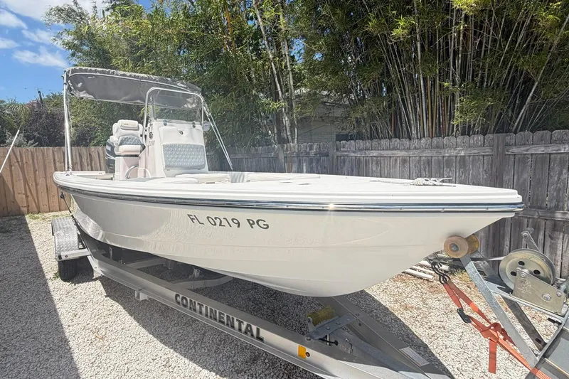 The Image of 2012 Pathfinder 2200 T boat on trailer, parked outdoors near wooden fence. - 1