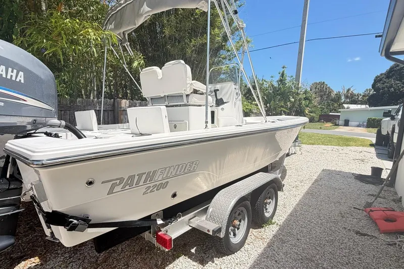 Slide: The Image of 2012 Pathfinder 2200 T boat on trailer, parked outdoors under clear blue sky. - 12
