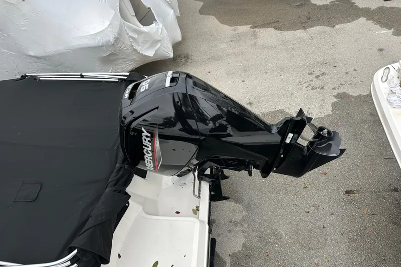 Slide: The Image of 2023 Bayliner Element M17 with Mercury outboard motor, covered and parked on pavement. - 24