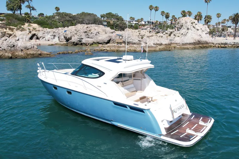 Slide: The Image of 2012 Tiara Yachts 4500 Sovran cruising near rocky coastline and palm trees. - 7