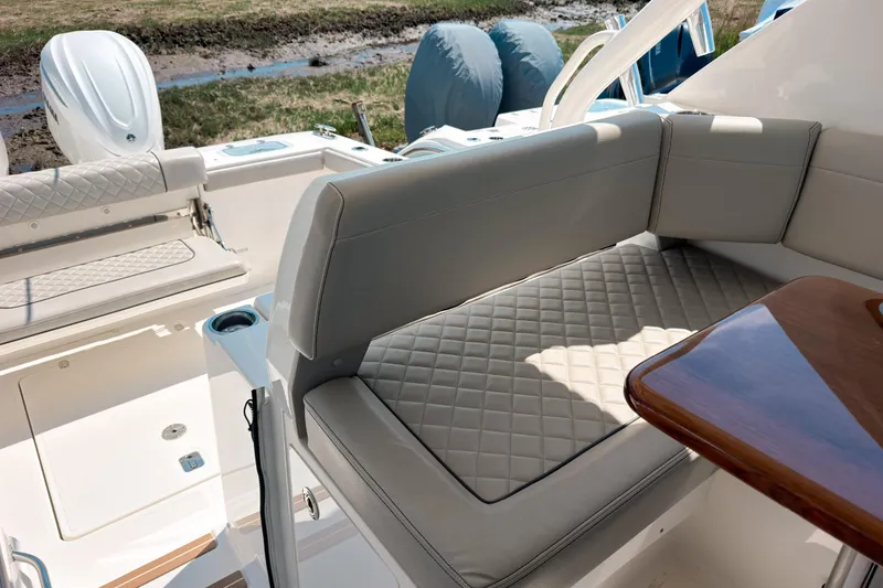 Slide: The Image of 2025 Pursuit OS 325 Offshore boat interior with cushioned seating and wooden table. - 11