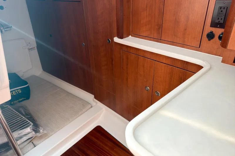 Slide: The Image of 2025 Pursuit OS 325 Offshore cabin interior with wood cabinetry and white countertop. - 13