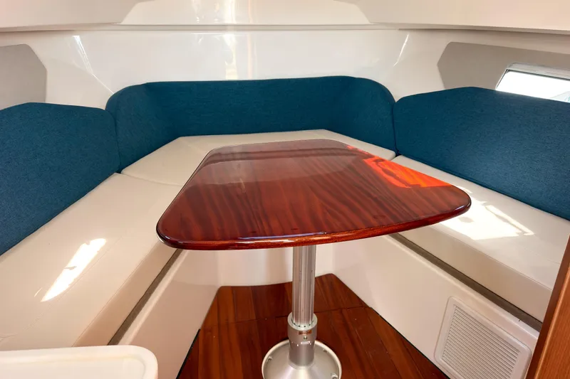 Slide: The Image of 2025 Pursuit OS 325 Offshore cabin with blue seating and wooden table. - 16