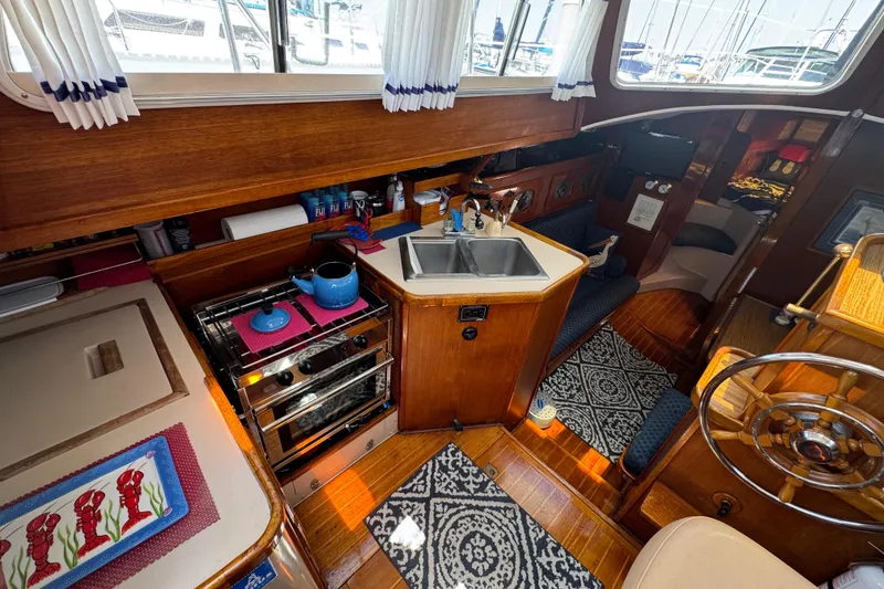 Slide: The Image of 1989 Gulf Pilot House interior with wooden cabinetry, stove, sink, and nautical decor. - 30