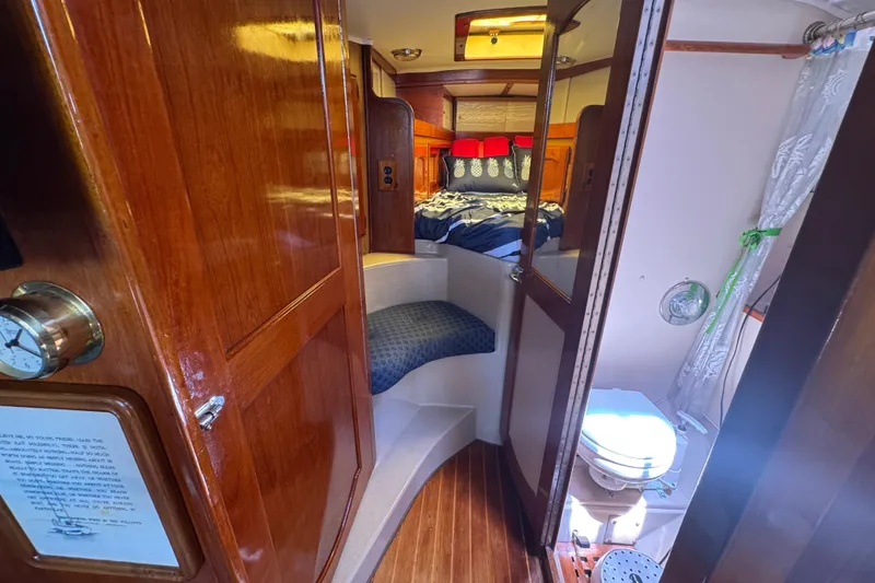 Slide: The Image of 1989 Gulf Pilot House interior with wooden finish, cozy bed, and compact bathroom. - 38