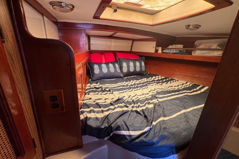 Slide: The Image of Cozy cabin interior of 1989 Gulf Pilot House with striped bedding and pineapple pillows. - 43