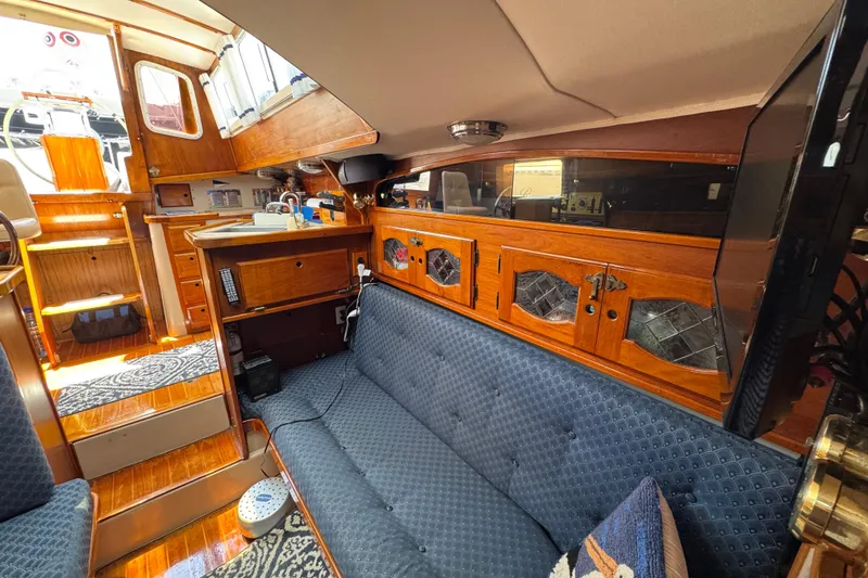 Slide: The Image of Interior of a 1989 Gulf Pilot House boat with wooden cabinetry and blue seating. - 50