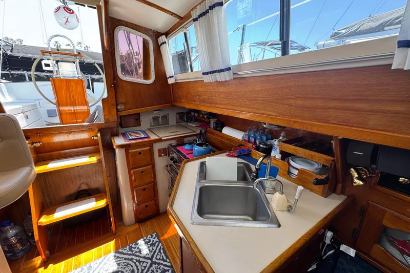 Slide: The Image of 1989 Gulf Pilot House interior with wooden cabinetry, sink, and nautical decor. - 54