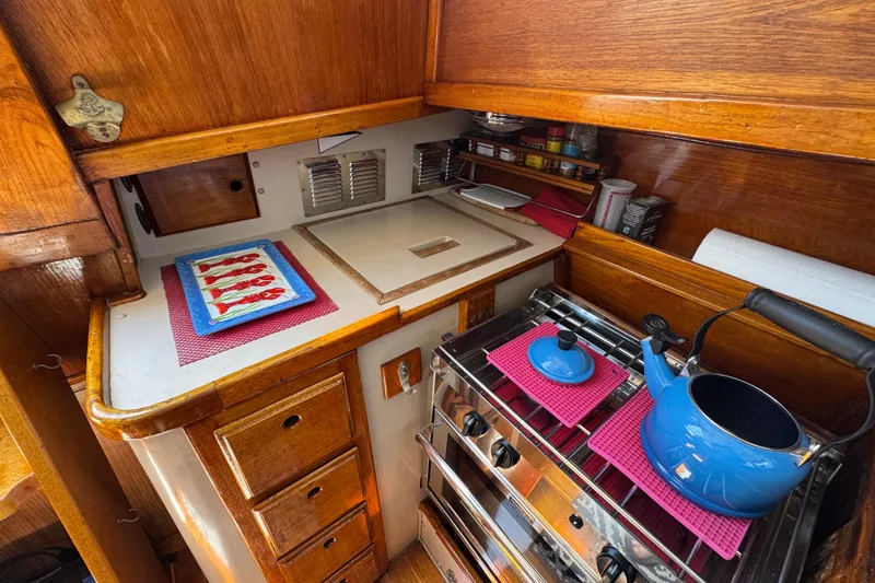 Slide: The Image of Cozy 1989 Gulf Pilot House kitchen with wooden cabinetry and blue kettle on stove. - 55