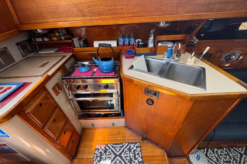 Slide: The Image of 1989 Gulf Pilot House kitchen with stove, sink, and wooden cabinetry. - 72