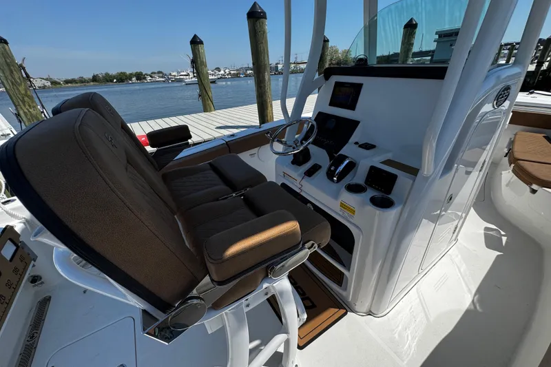 Slide: The Image of 2024 Sea Pro 239 Deep V CC boat interior with helm and seating, docked by the water. - 75