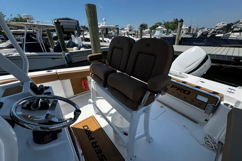 Slide: The Image of 2024 Sea Pro 239 Deep V CC boat interior with brown seating at marina. - 77