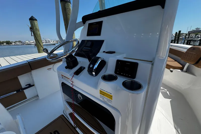 Slide: The Image of 2024 Sea Pro 239 Deep V CC boat console with steering wheel and controls, dockside view. - 79
