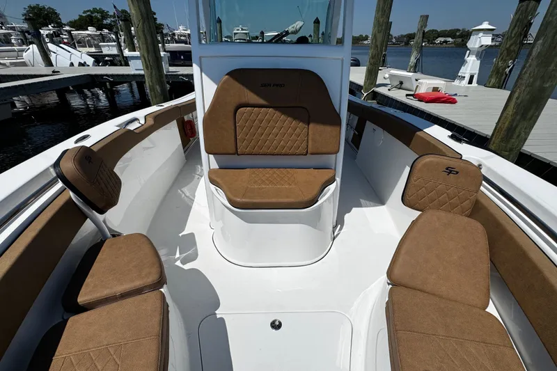 Slide: The Image of 2024 Sea Pro 239 Deep V CC boat interior with brown cushioned seating at a marina. - 96