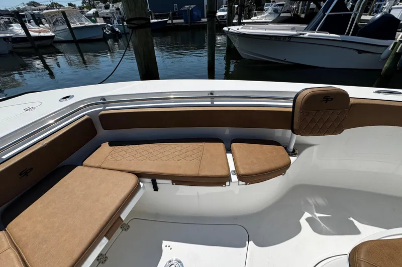 Slide: The Image of 2024 Sea Pro 239 Deep V CC boat interior with tan cushioned seating at marina. - 98